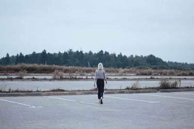 Rear view of man standing on shore against sky