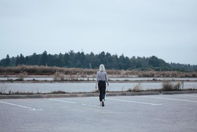 Rear view of woman walking on street against sky