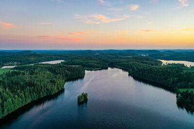 Aerial view of a blue lake and forest during sunset in finland