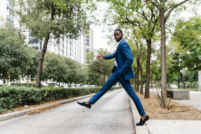 Playful young male professional with hand in pocket crossing street in city