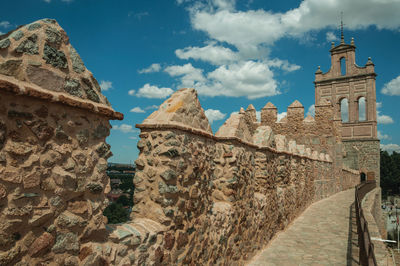 Pathway over old thick wall with battlement made of stone encircling the town, in avila,spain.