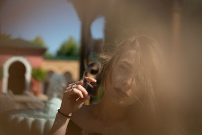 Portrait of woman holding film reel against sky