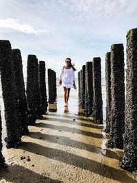 Full length of young woman standing against sky