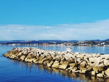 Sailboats in marina at harbor against blue sky