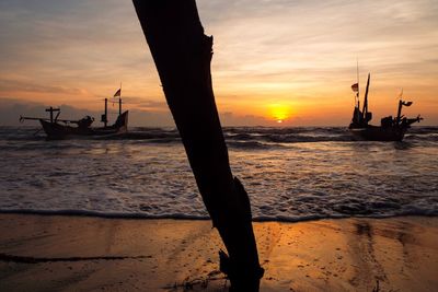 Silhouette boat on beach against sky during sunset