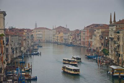 Boats in canal amidst buildings in city against clear sky