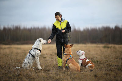 Full length of woman with dogs on field