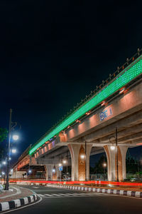 Illuminated bridge over river against sky at night