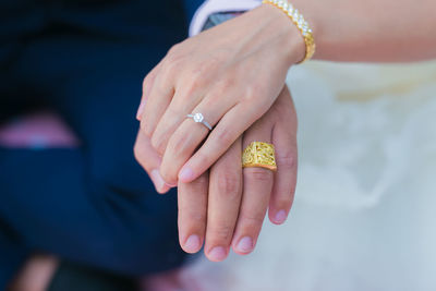 Cropped image of bride and bridegroom wearing wedding rings