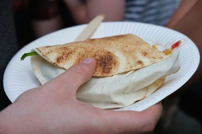 Close-up of hand holding bread in plate