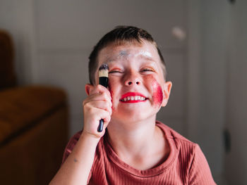 Charming child with makeup applicator looking away at table with eyeshadow palette