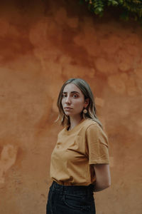 Portrait of woman standing against wall