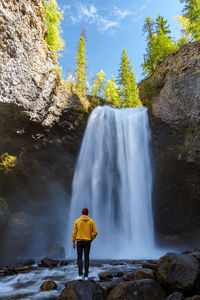 Rear view of woman standing against waterfall