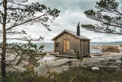 Wooden hut on beach against sky