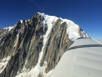 View of snowcapped rocky mountain by airplane wing