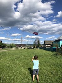 Rear view of boy on field against sky