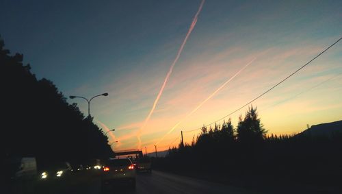 Cars on road against sky at sunset