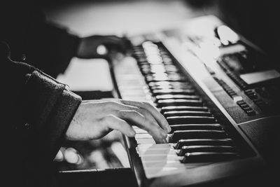 Cropped hands of man playing piano at home