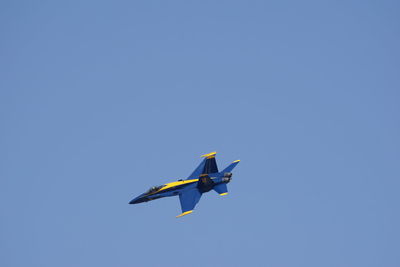 Low angle view of airplane flying against clear blue sky