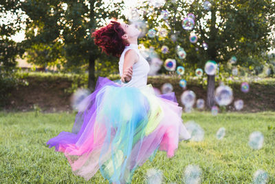 Woman dancing on field against trees