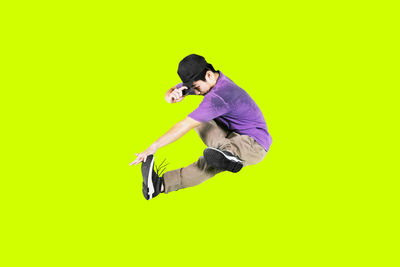 Side view of young man jumping against white background