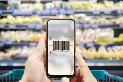 Midsection of person using mobile phone at store