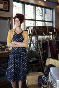 Portrait of female owner with arms crossed standing in clothing store