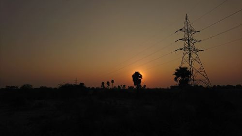 Silhouette birds on landscape against sky at sunset