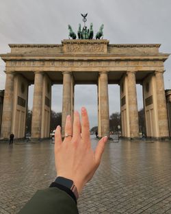 Cropped image of person hand against historic building