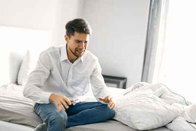 Frustrated young man sitting on bed