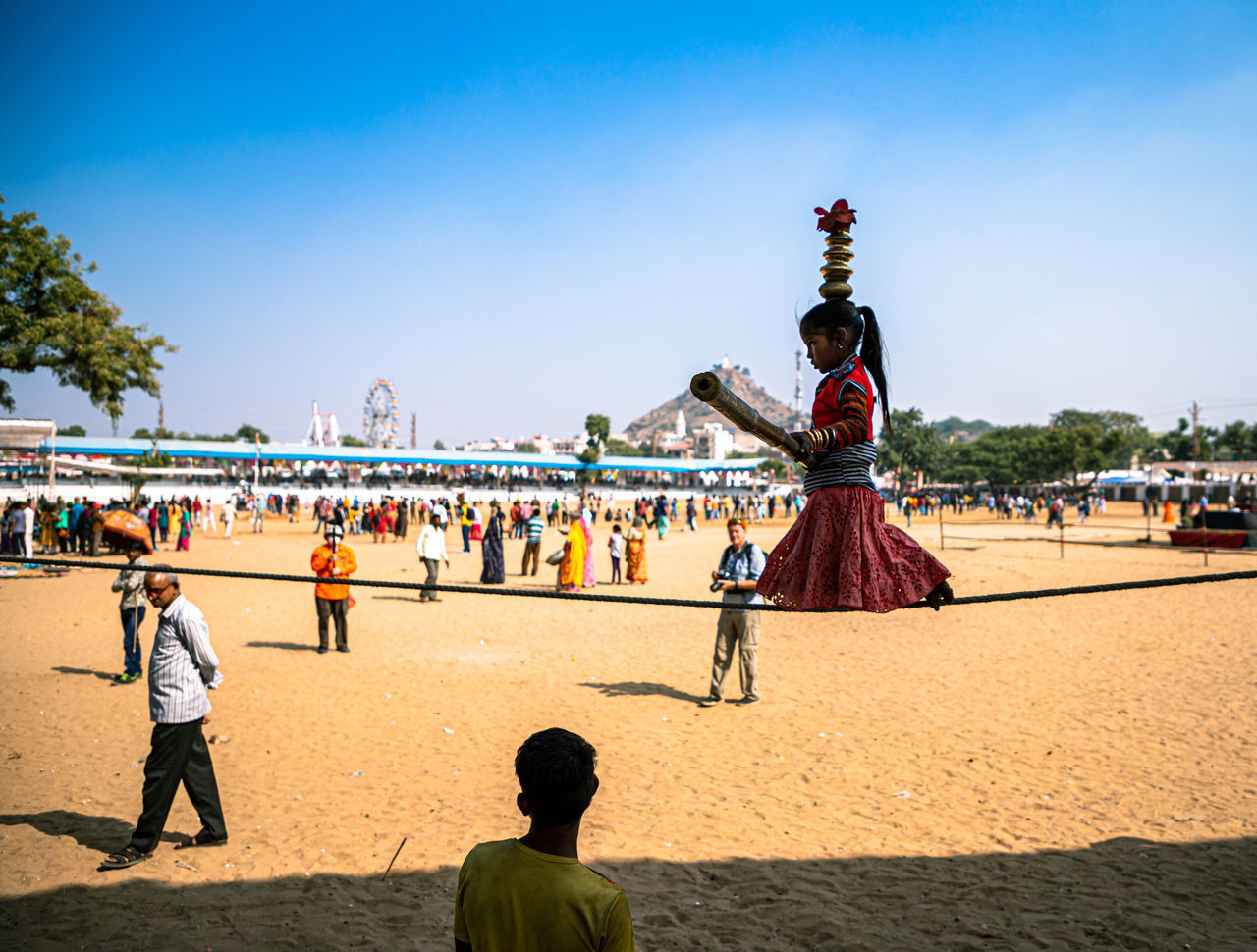 REAR VIEW OF PEOPLE ON BEACH AGAINST SKY