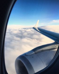 View of airplane wing over clouds seen through window