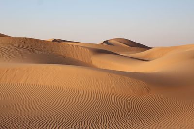 Sand dunes in desert against clear sky