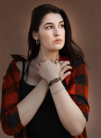 Portrait of young woman standing against gray background