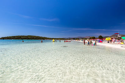 People on beach against blue sky