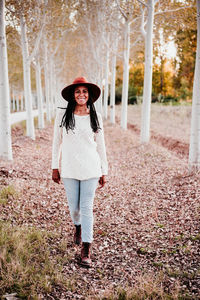 Full length portrait of young woman standing in park during autumn