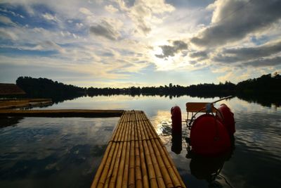 Rear view of man on pier over lake against sky