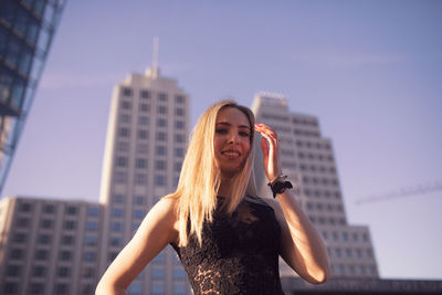 Portrait of young woman standing against modern building in city