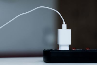 Close-up of electric lamp on table against white wall