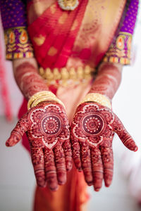 Midsection of bride wearing sari and jewelry while showing henna tattoo