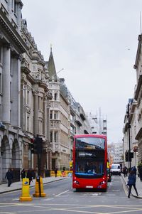 Cars on city street by buildings against sky