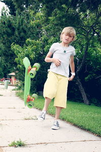 Boy kicking skateboard on footpath at park