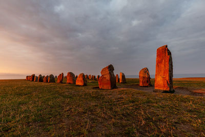 Rocks on field against sky during sunset