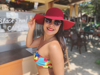 Portrait of smiling young woman wearing sunglasses standing outdoors