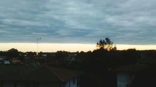 Silhouette houses in town against sky during sunset