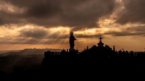 Silhouette people standing by building against sky during sunset