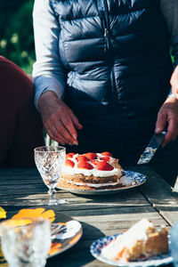 Midsection of woman standing by cake in back yard