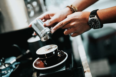 Midsection of person having coffee in cafe