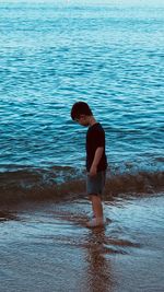 Full length side view of boy standing on sea shore