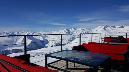 Snow covered railing by mountain against sky